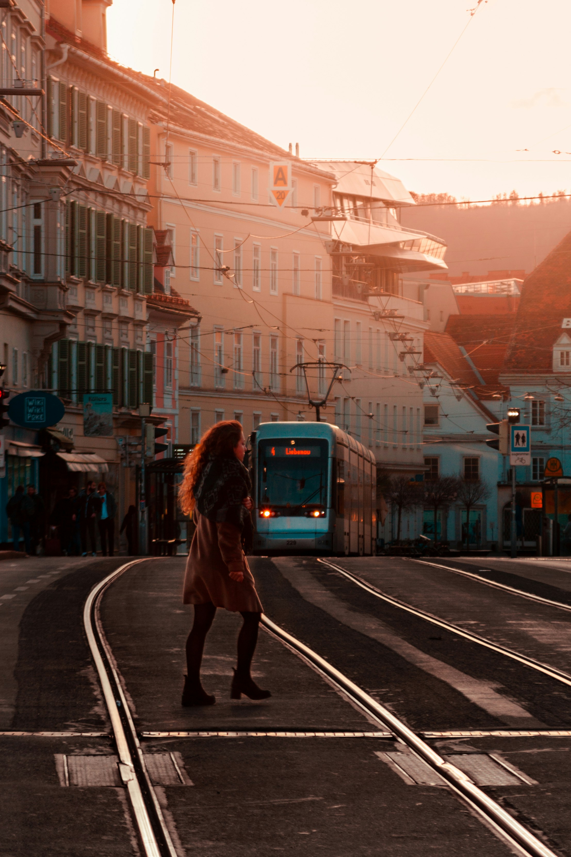 a woman walking across a street next to a train