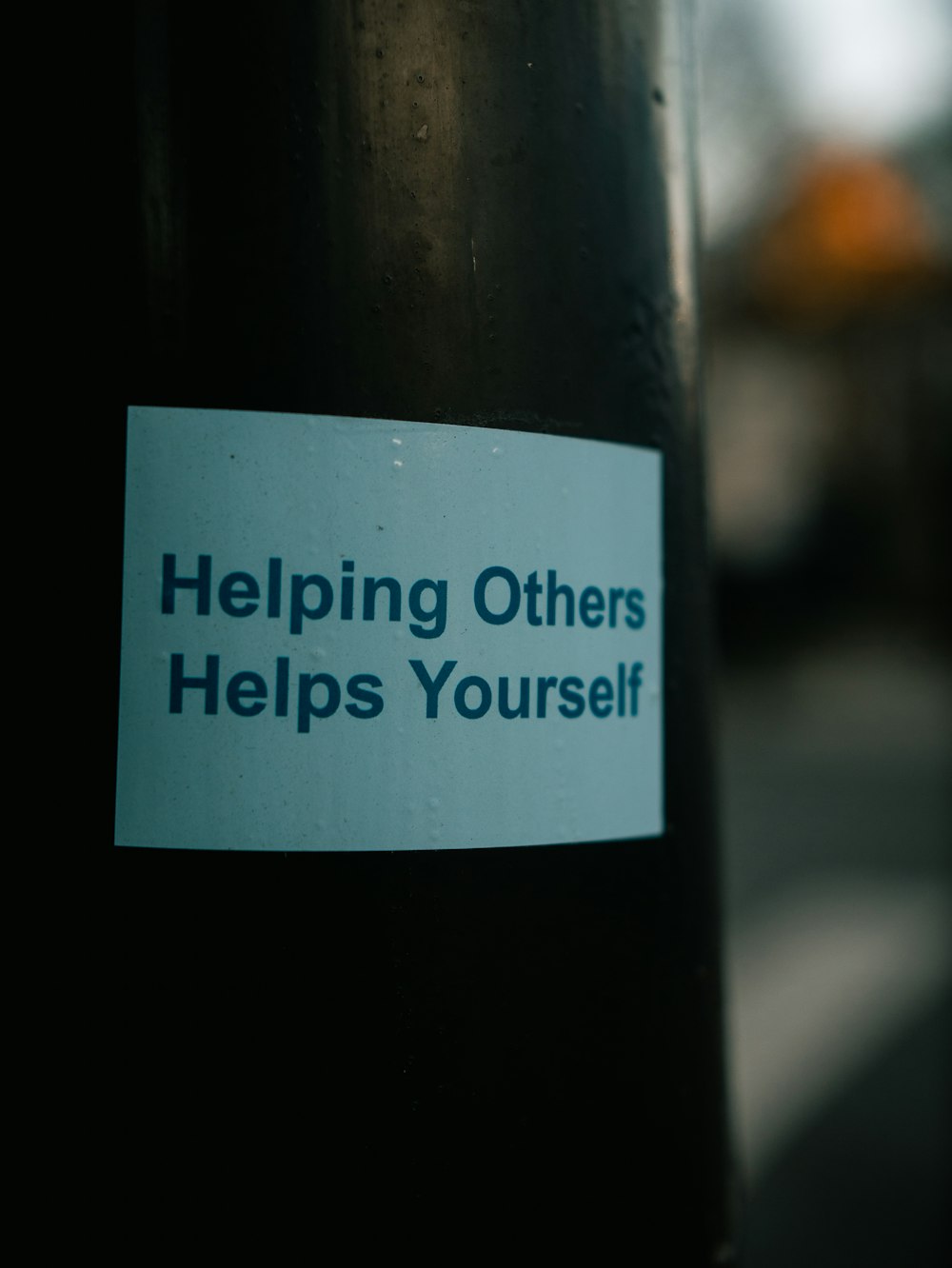 a sticker on a pole that says helping others helps yourself