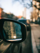 Side mirror reflecting a city street scene, illustrating both functionality and style.