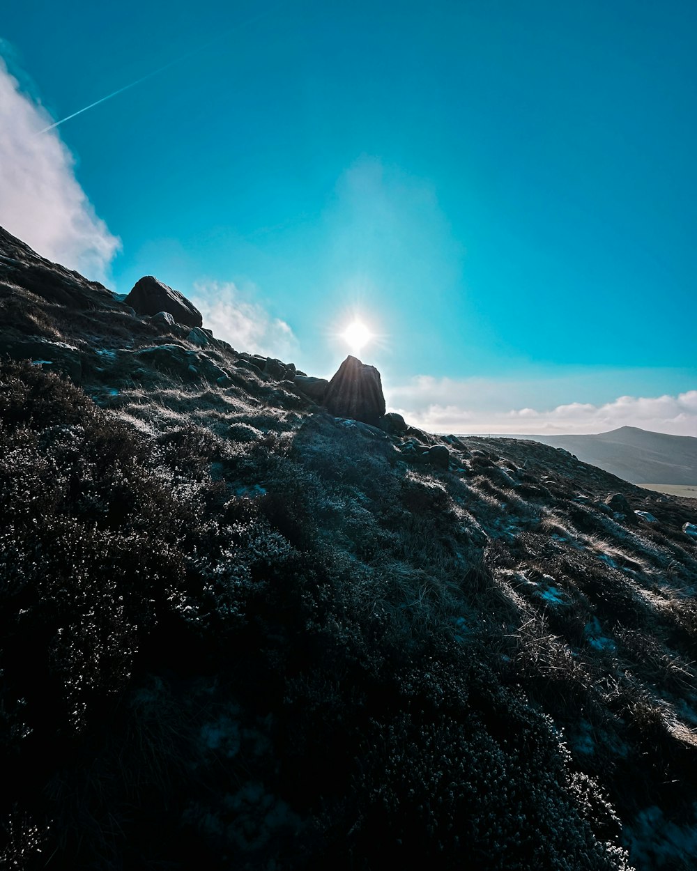 the sun is shining over a rocky hill