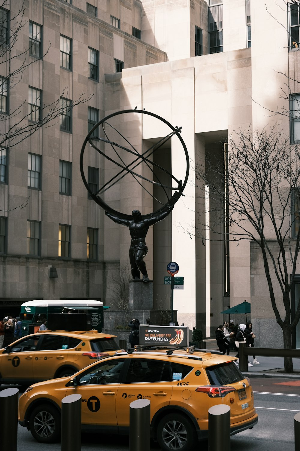 uma cena de rua com táxis e uma estátua