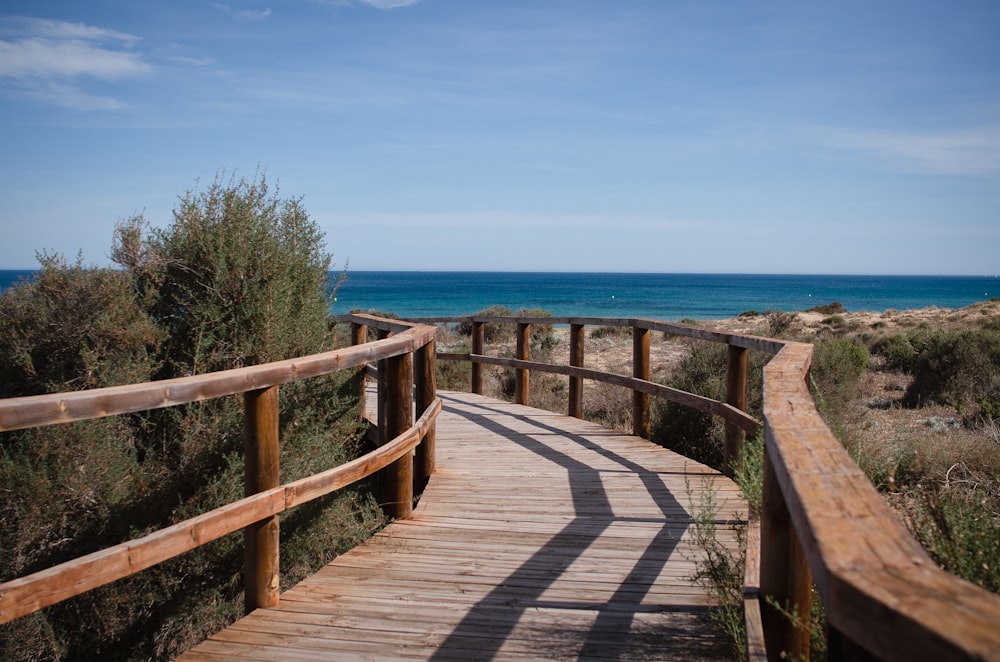 a wooden walkway leading to the ocean on a sunny day