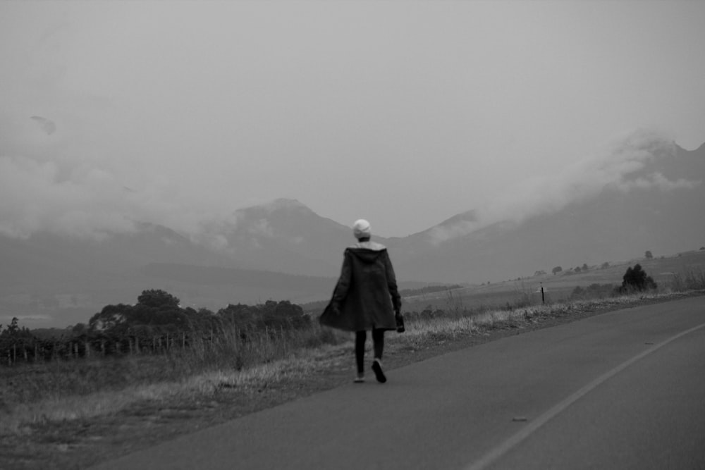 a woman walking down a road in the middle of nowhere