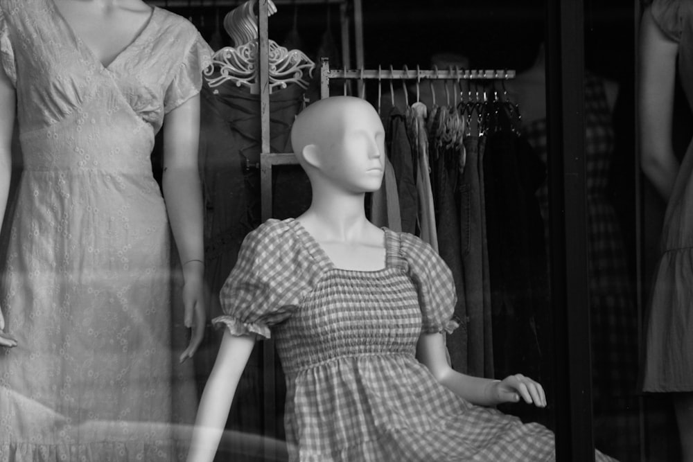 a black and white photo of mannequins in a store window