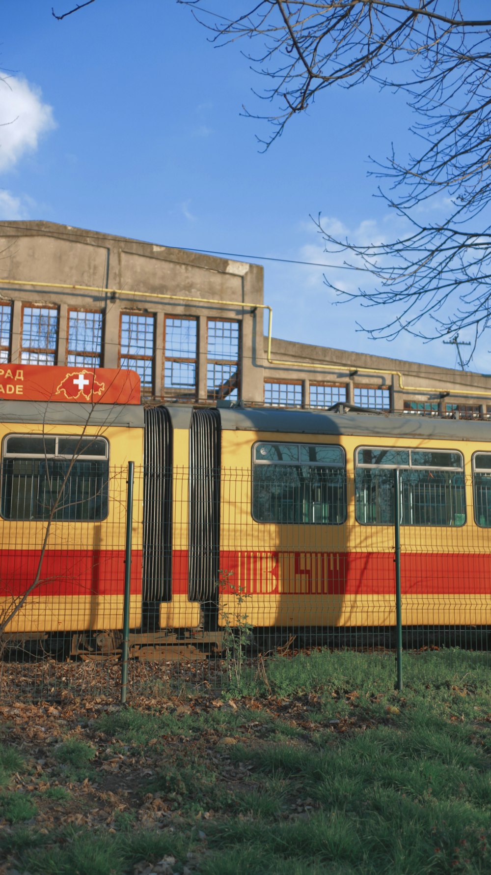 a yellow and red train parked in front of a building
