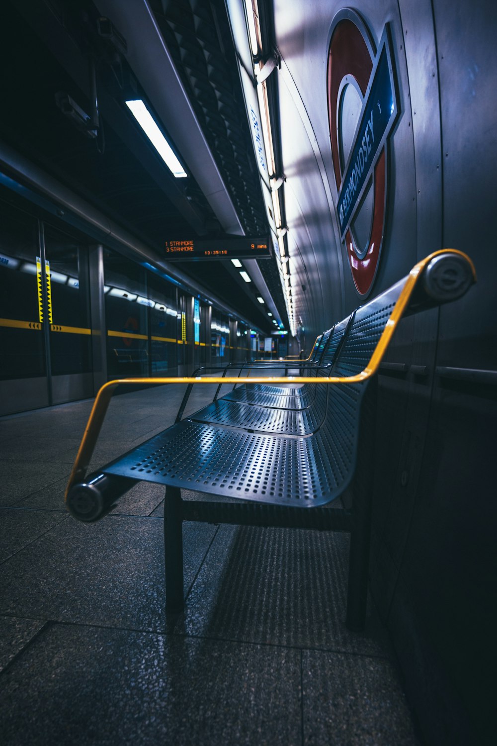 a train station with a metal bench and a yellow rail