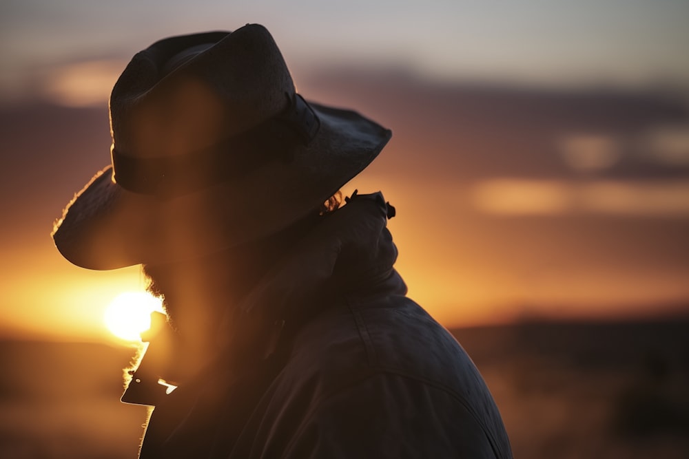 a person wearing a hat and a coat with the sun in the background