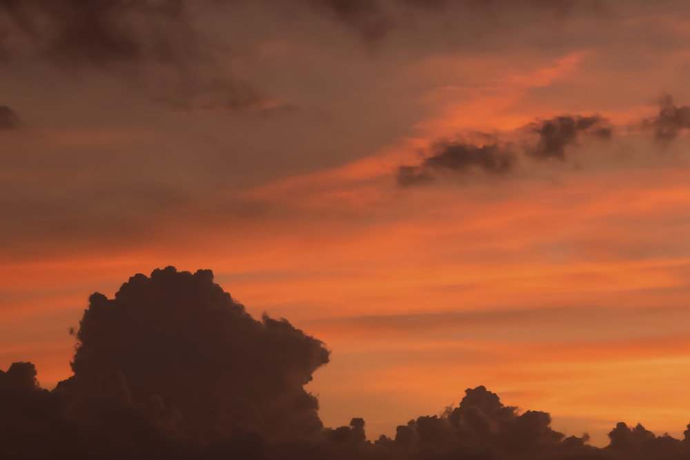 a plane flying in the sky at sunset