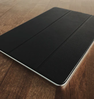 A sleek tablet resting on a wooden desk with a soft natural light highlighting its screen.