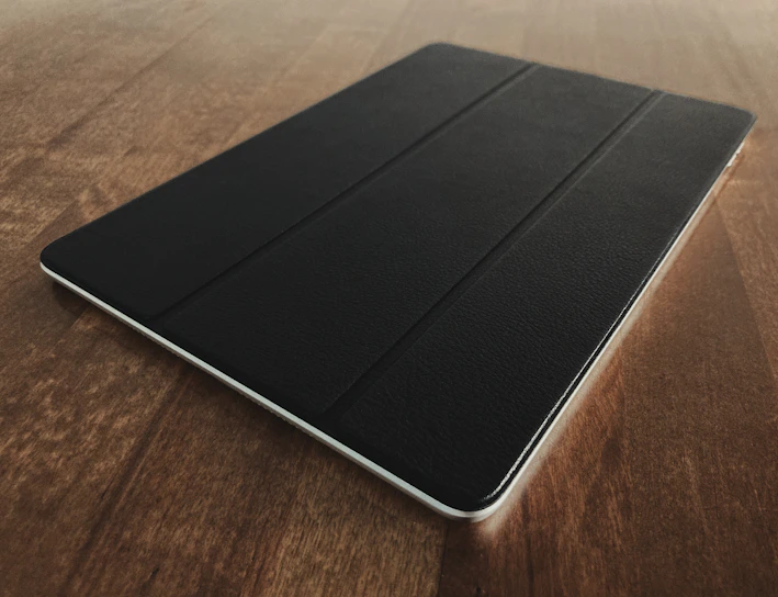 A sleek tablet resting on a wooden desk with a soft natural light highlighting its screen.