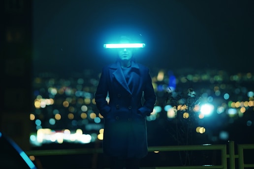 a man in a suit and hat standing in front of a city at night