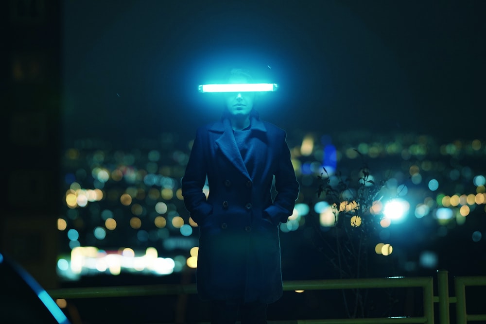 a man in a suit and hat standing in front of a city at night