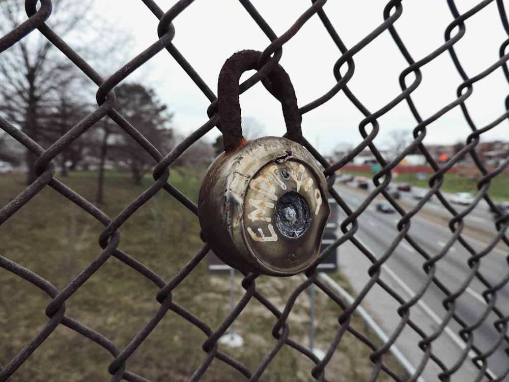 a padlock on a chain link fence near a highway