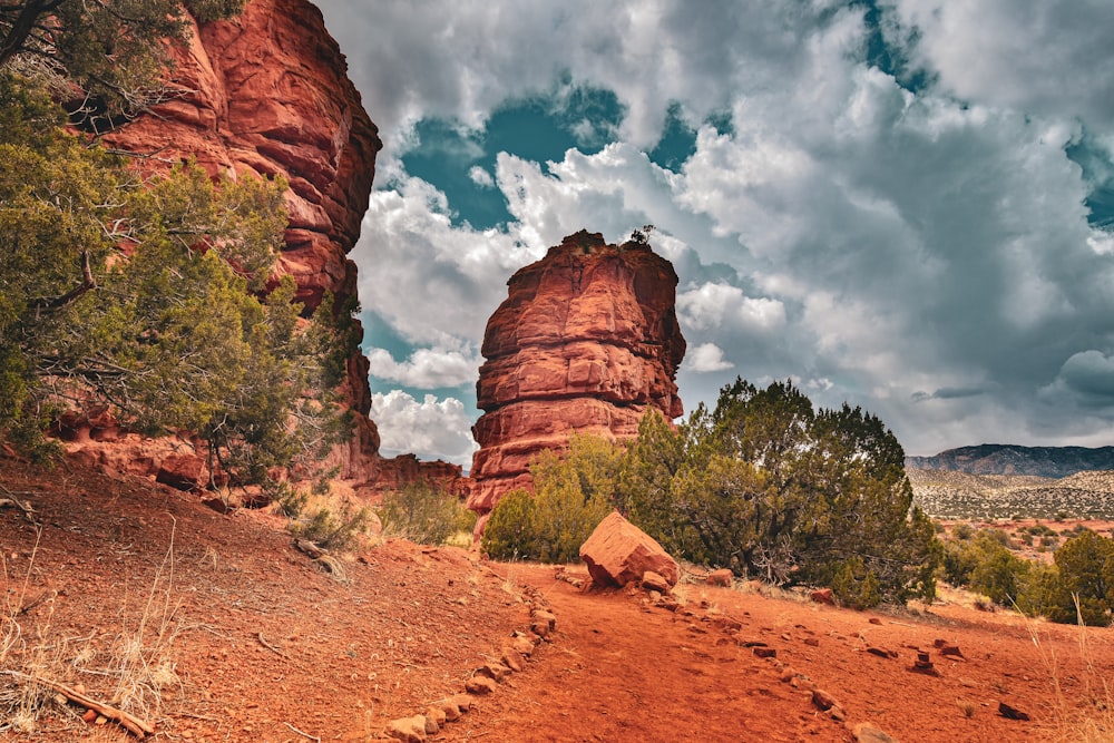 a dirt path with a rock formation in the background