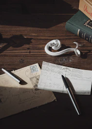 A close-up of vintage coins and stamps arranged on a wooden table with soft natural light.