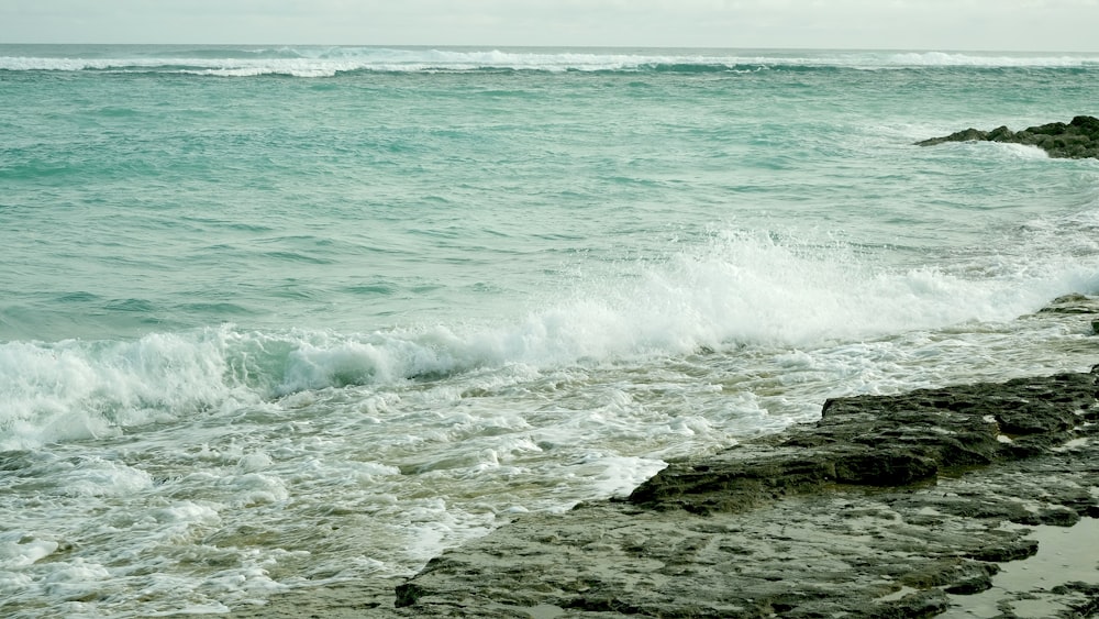 a person standing on a rocky beach next to the ocean