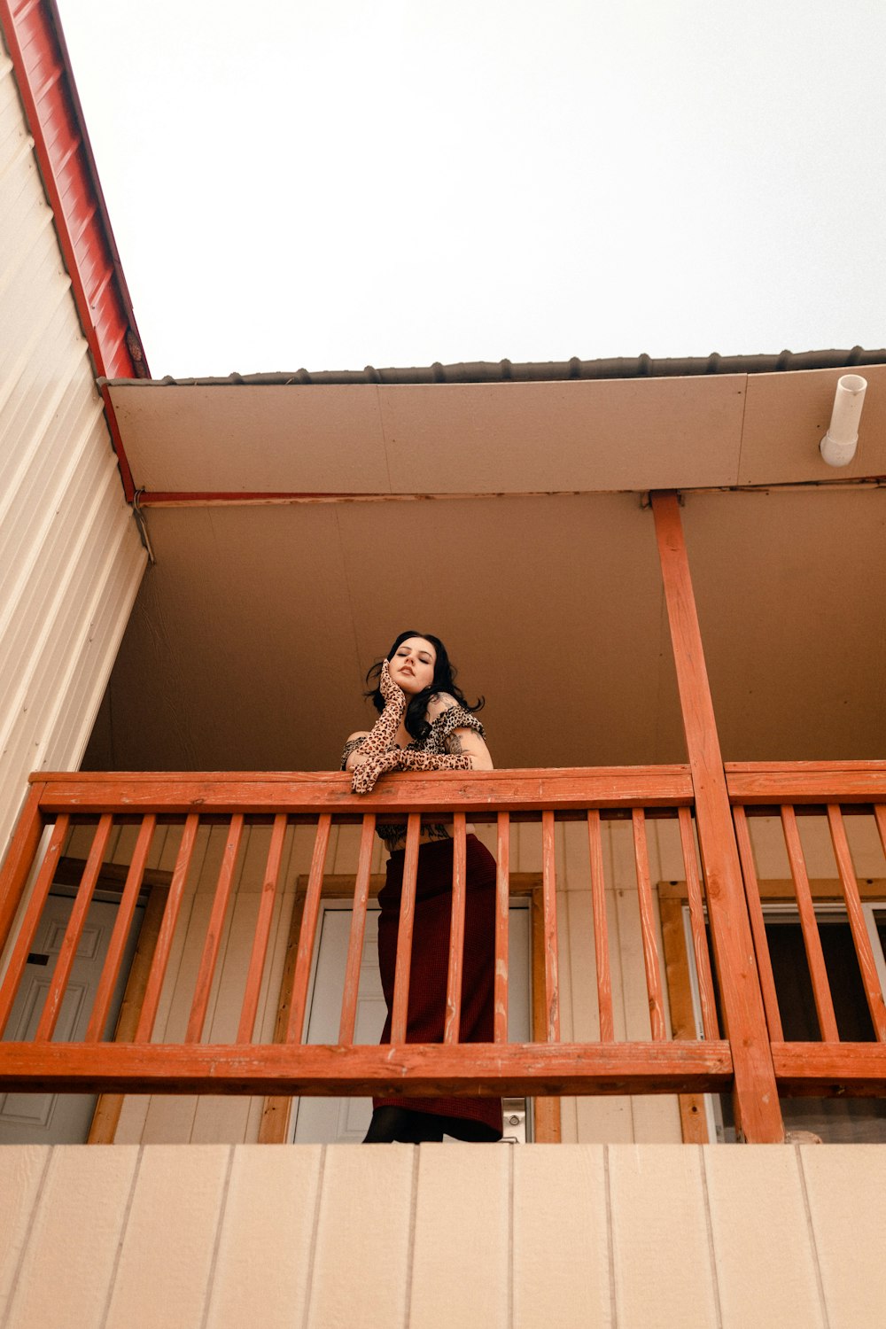 a woman standing on a balcony talking on a cell phone