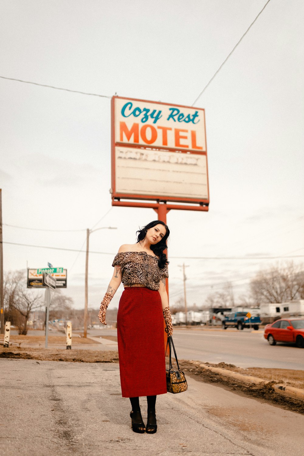 a woman in a red skirt holding up a motel sign