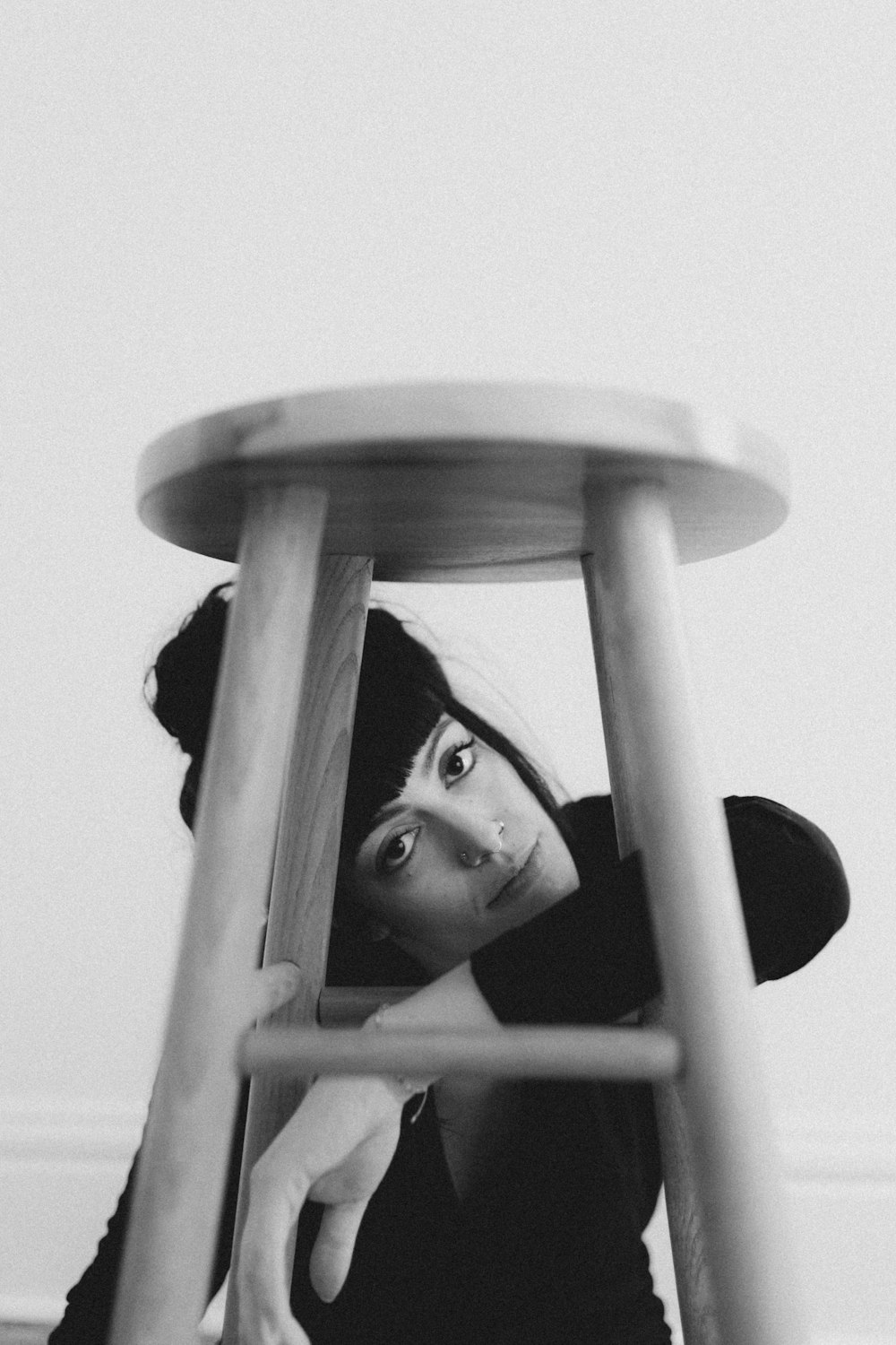 a black and white photo of a woman leaning on a stool