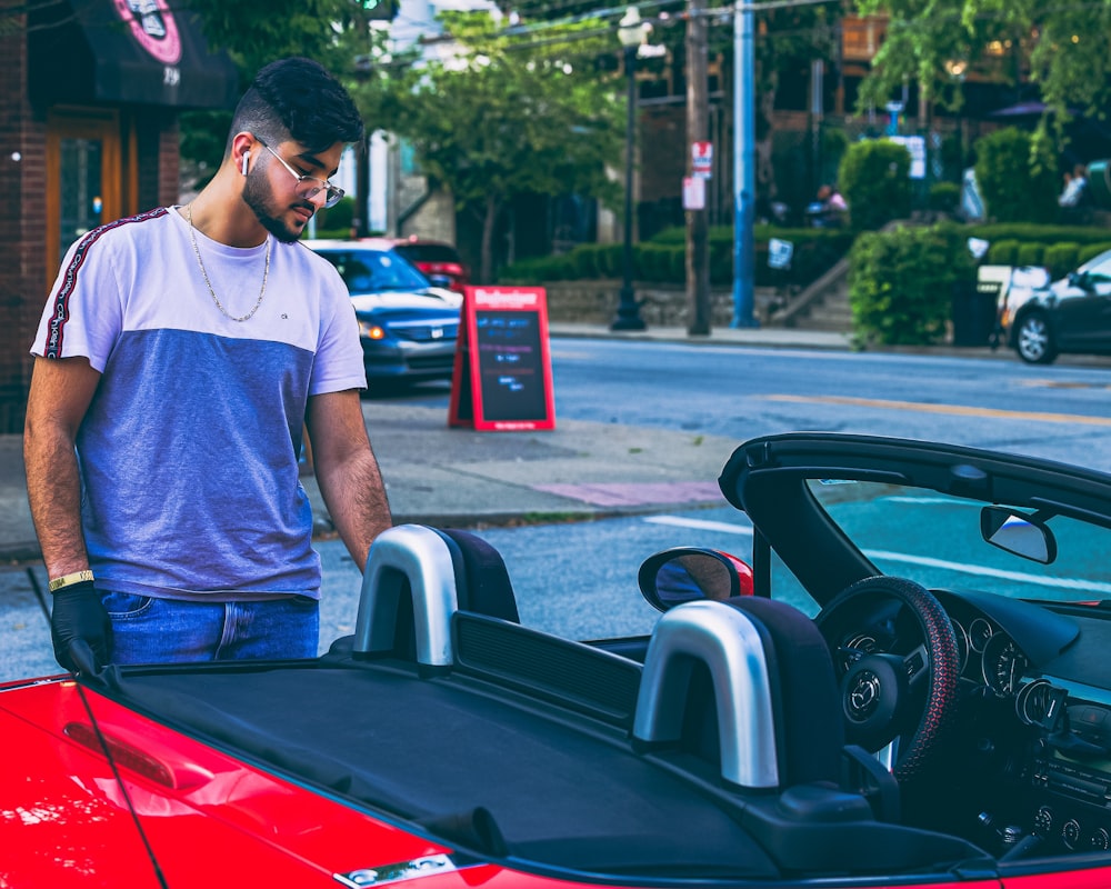 a man standing next to a red sports car