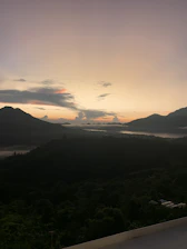 A serene view of the Eastern Plains of Colombia at sunset, with lush greenery and distant mountains.