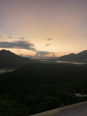 A serene view of the Eastern Plains of Colombia at sunset, with lush greenery and distant mountains.
