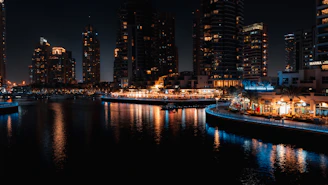 Nighttime panorama of Dubai Marina illuminated with city lights reflecting on the water.