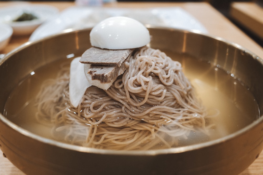 a bowl of noodles with a boiled egg on top