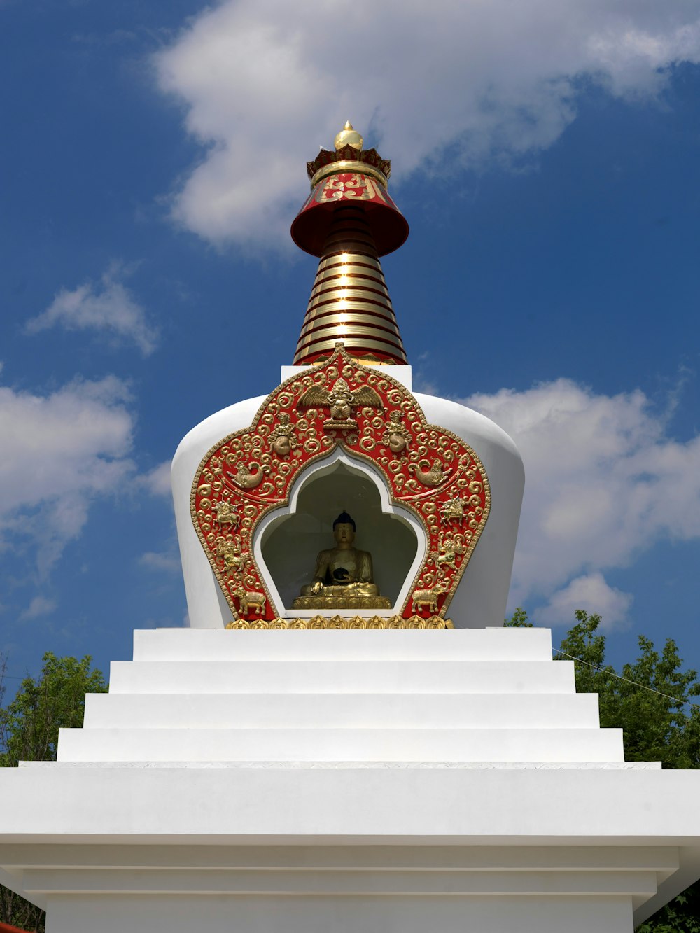 Una estatua dorada y roja en la parte superior de una estructura blanca