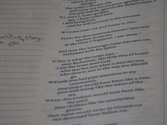 A close-up of a page from a book with text printed in a serif font. There are handwritten notes on the left margin, while the right side contains printed passages. The text is aligned in two columns.