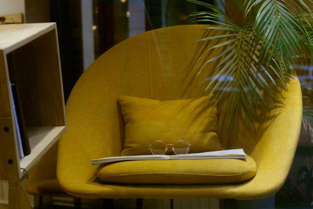 a yellow chair with a book and some glasses on it