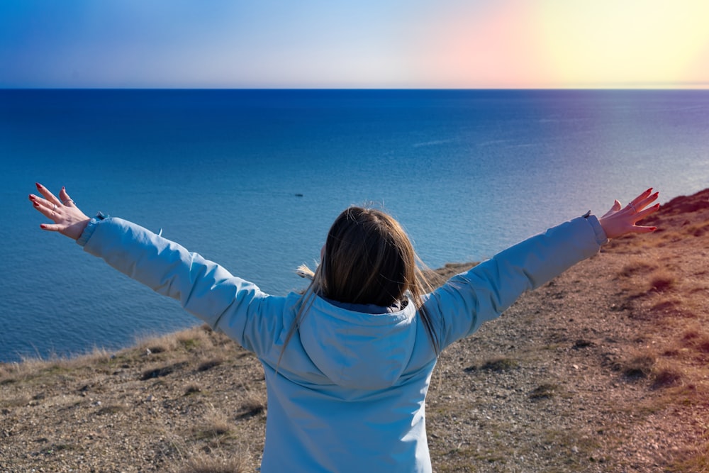 a woman standing on top of a hill next to the ocean