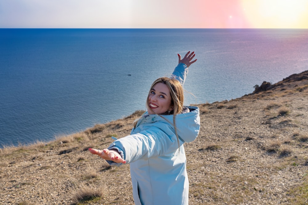 uma mulher em pé no topo de uma colina perto do oceano