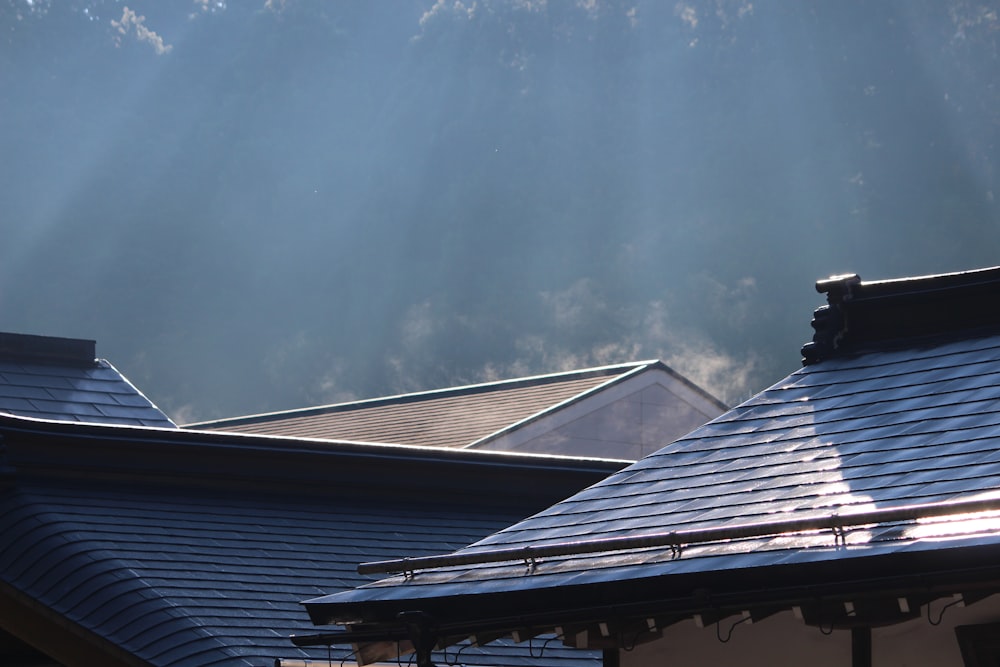 o telhado de uma casa com o sol brilhando através das nuvens