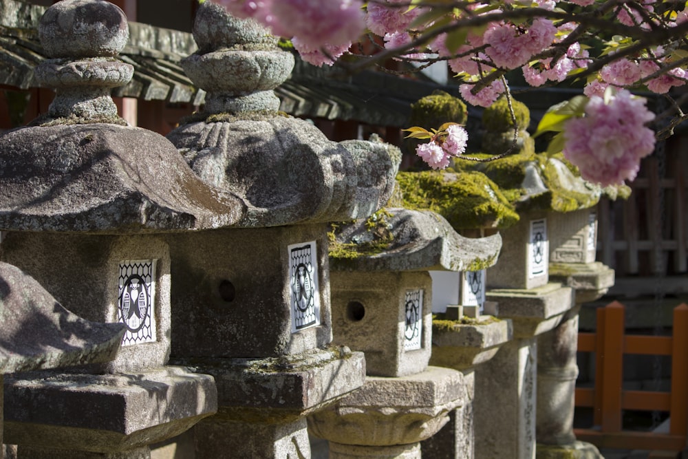 a row of stone birdhouses with pink flowers in the background