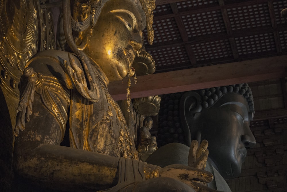 uma estátua de uma pessoa sentada na frente de uma estátua de Buda