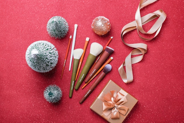 Animated graphic of swirling red and black makeup brushes with shimmering gold accents, reflecting Santa's brand theme.