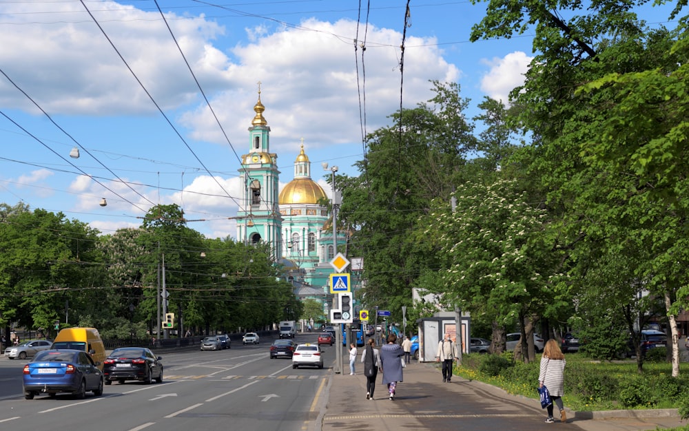 a group of people walking down a street next to a church