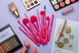 Flat lay of colorful lipsticks and blushes with fresh flowers around.
