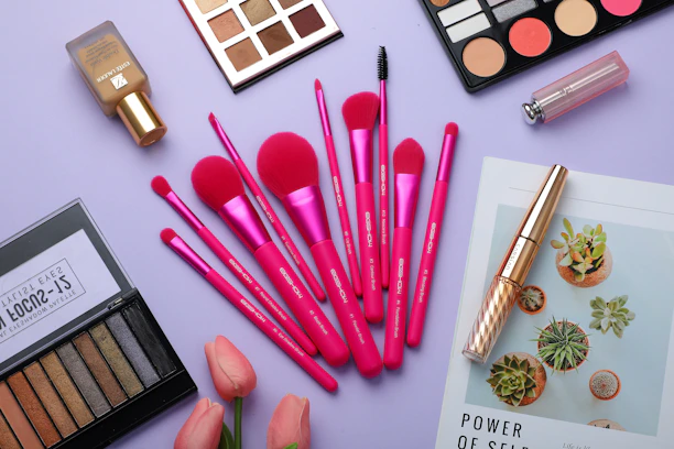A vibrant flat lay of foundation bottles, soft makeup brushes, and sleek beauty tools on a marble surface.