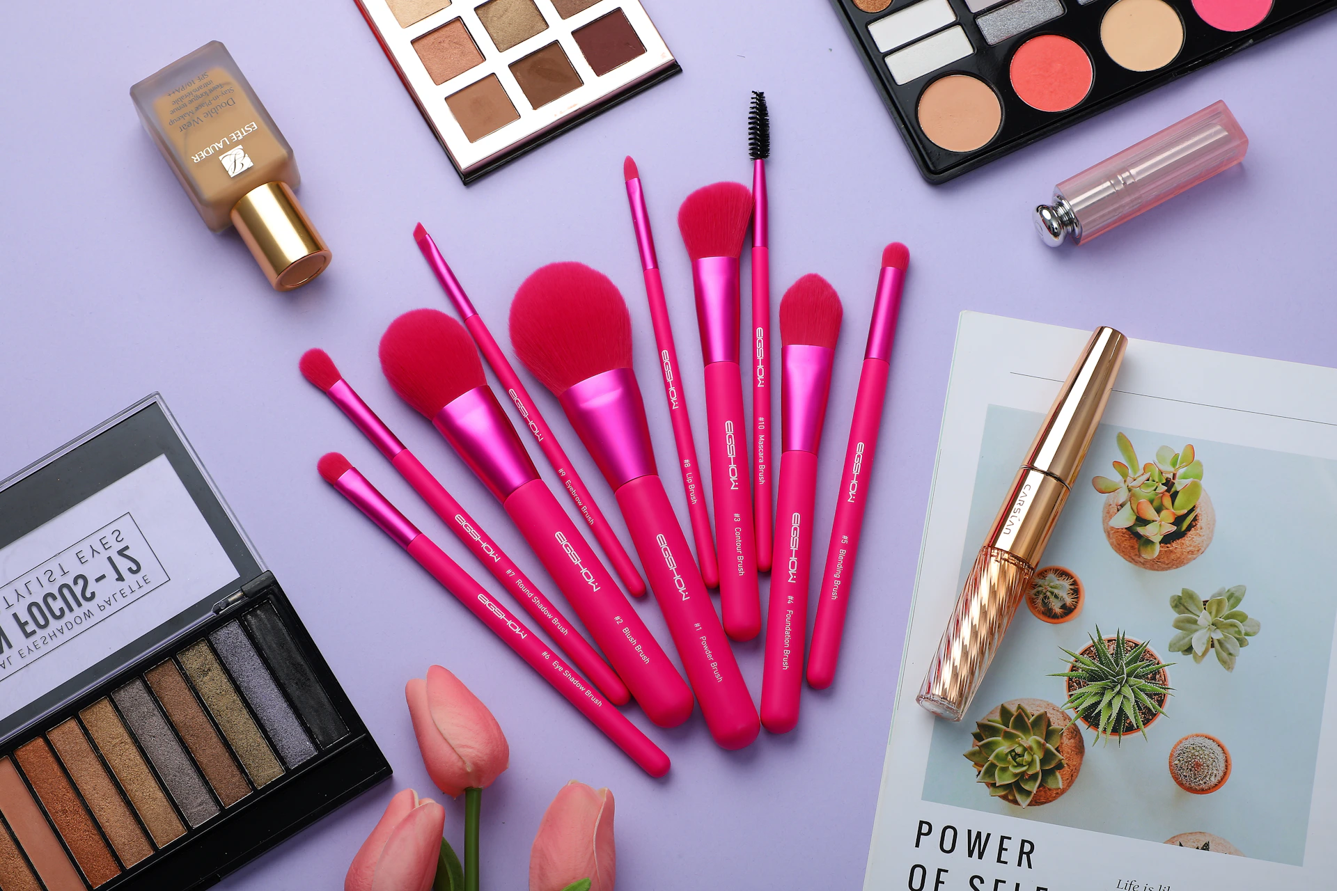 A vibrant flat lay of colorful makeup products trending on TikTok, including lip glosses, eyeshadow palettes, and blushes, styled with fresh flowers.