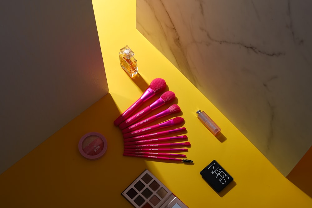 a yellow table topped with a bunch of pink brushes