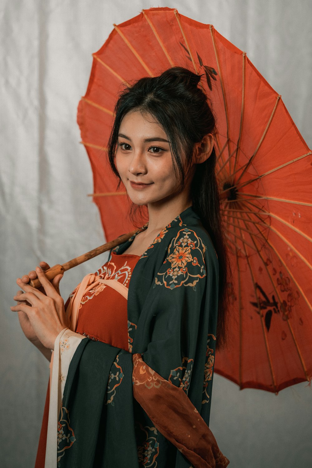 uma mulher em um quimono segurando um guarda-chuva laranja