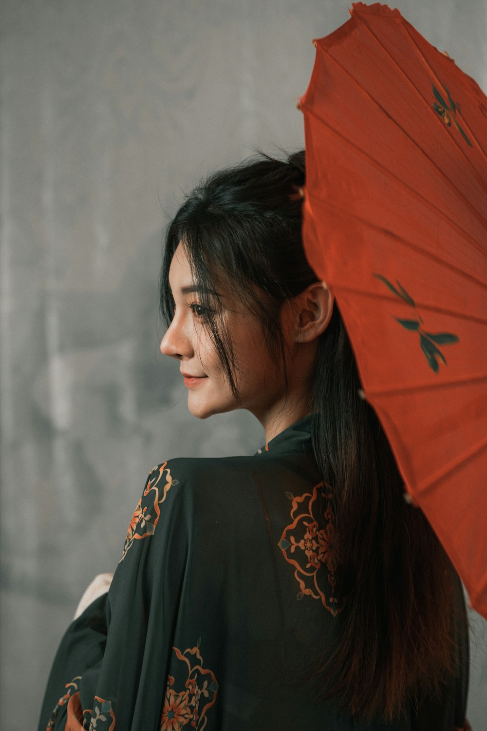 a woman with a red umbrella standing in front of a wall