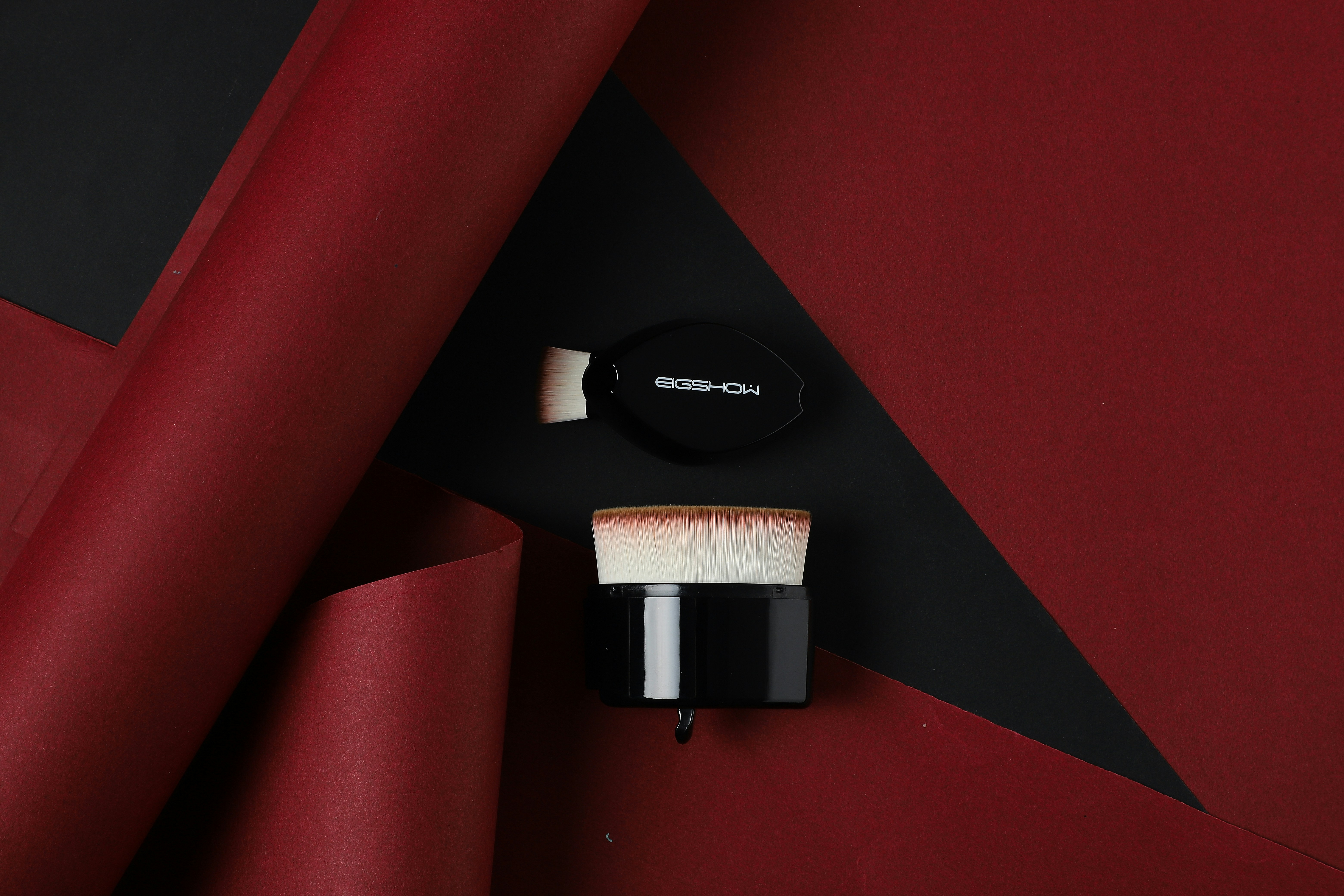 ein roter und schwarzer Hintergrund mit Make-up-Pinsel und Puder