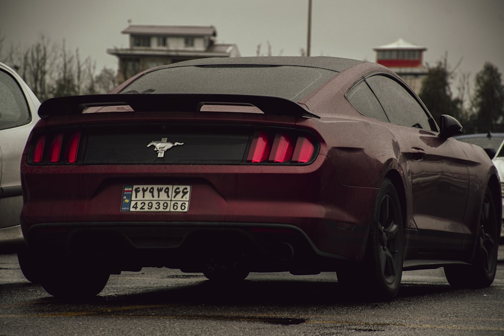a maroon mustang parked in a parking lot