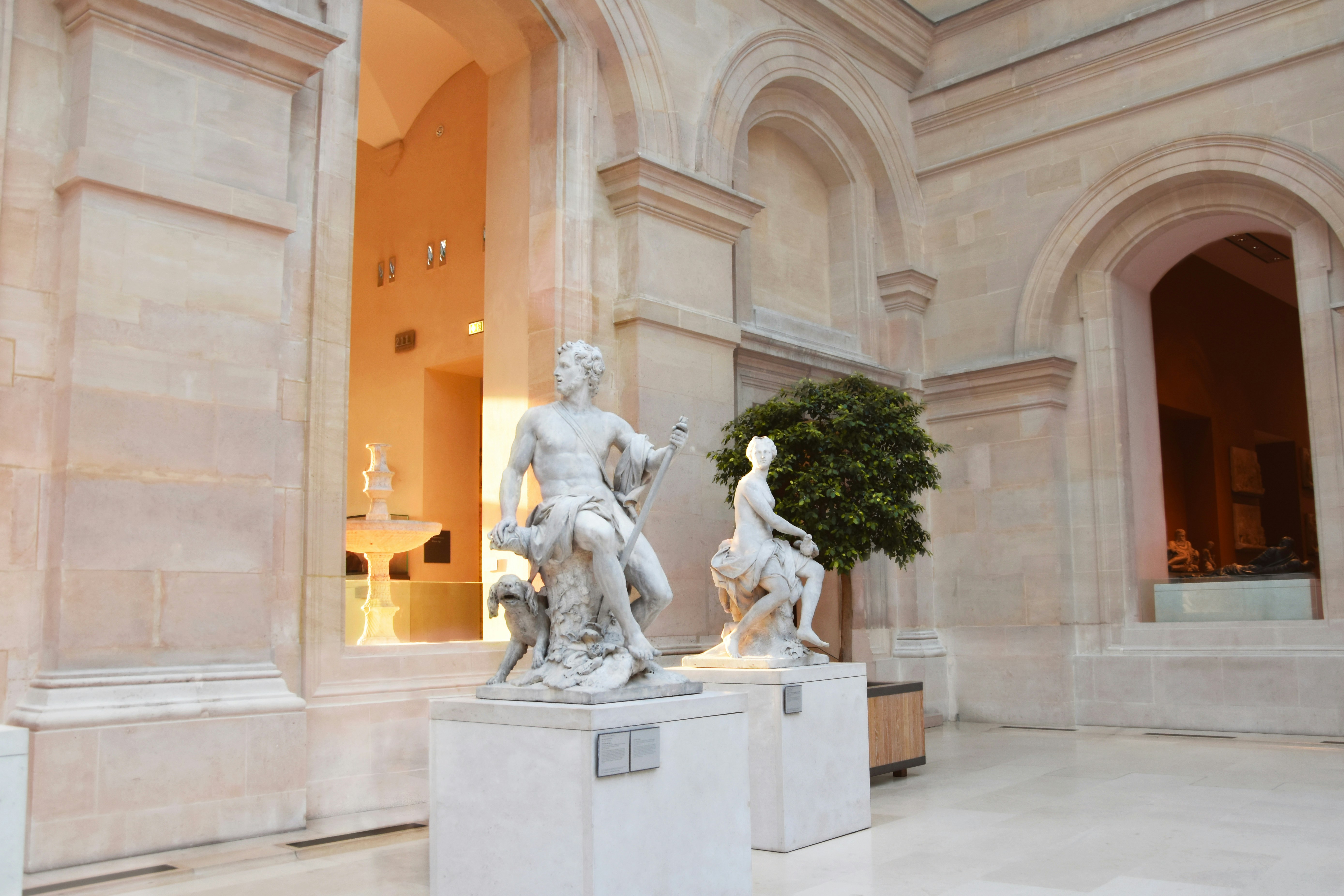 Interior of a grand art museum with high ceilings, marble floors, classical sculptures, warm ambient lighting