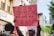 A person holds a pink protest sign in a street setting. The sign features illustrations of various women and a message advocating for women's rights, specifically addressing the policing of women's clothing. Several individuals are gathered around, some wearing masks, and buildings and trees are visible in the background.