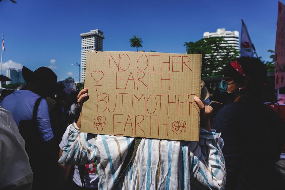 a group of people holding a sign that says no other earth but mother earth