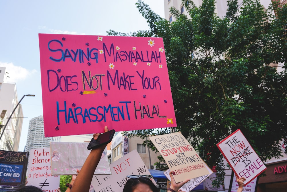 a woman holding a pink sign with writing on it